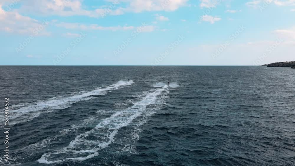 Aerial shot following two people having fun riding personal watercrafts on the sea Aerial shot following two people having fun riding personal watercrafts on the sea