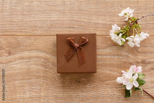 Gift box with cherry flowers on the wooden background.