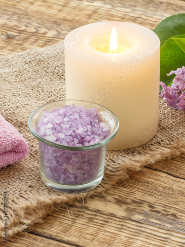 Sea salt  candle and lilac flowers on wooden background.