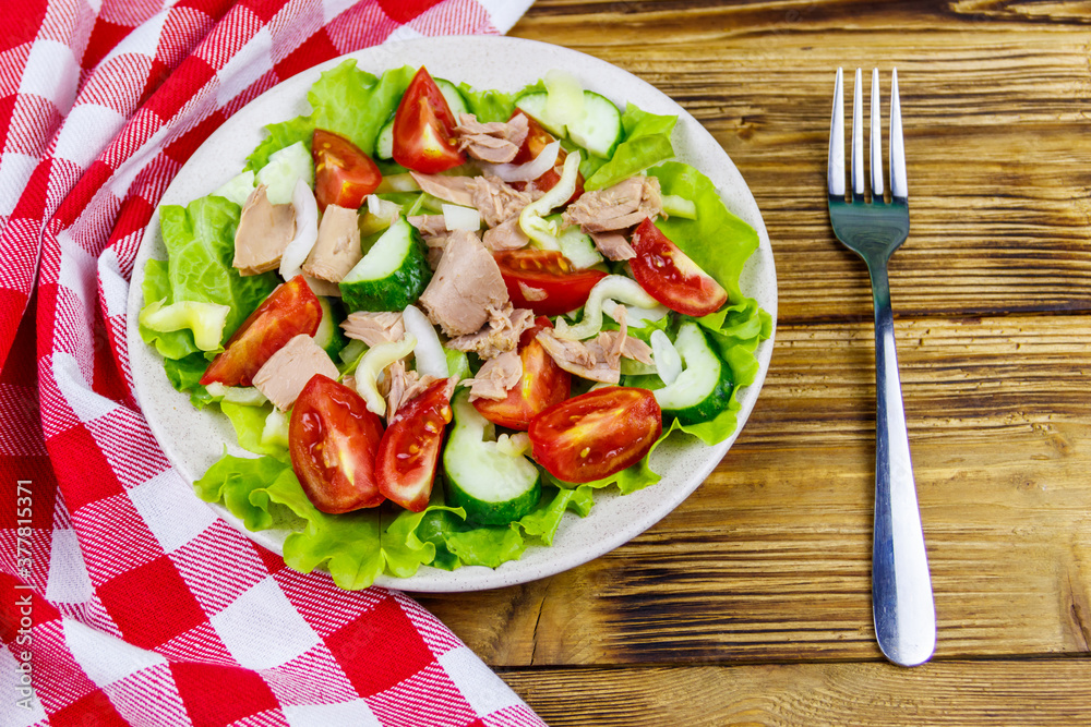 Tasty tuna salad with lettuce and fresh vegetables on wooden table. Top view Tasty tuna salad with lettuce and fresh vegetables on wooden table. Top view