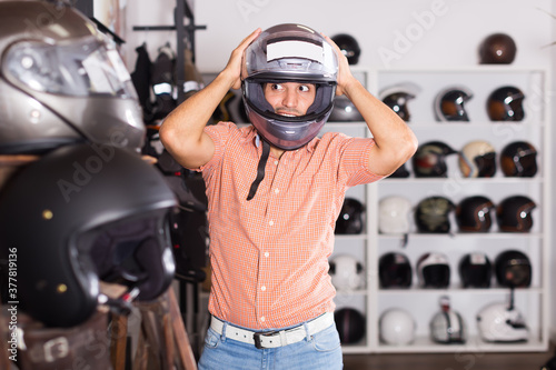 Young man is trying up new helmet for motorbike in the store
