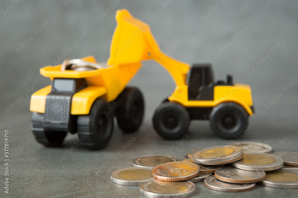 Dump truck, loader, coins stack on loft walls with sunlight  and copy space for money saving concept