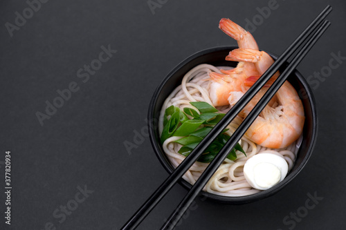 Healthy popular Asian street food. Close-up footage of traditional japanese ramen with shrimp, scallions and egg on black background. 