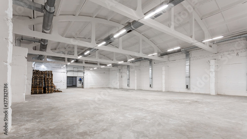 Industrial building interior with white brick walls, concrete floor and empty space for product display or industrial background
