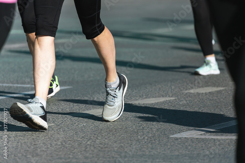 A close-up of the legs of the running track and field athletes on the asphalt. Marathon runners in special sneakers