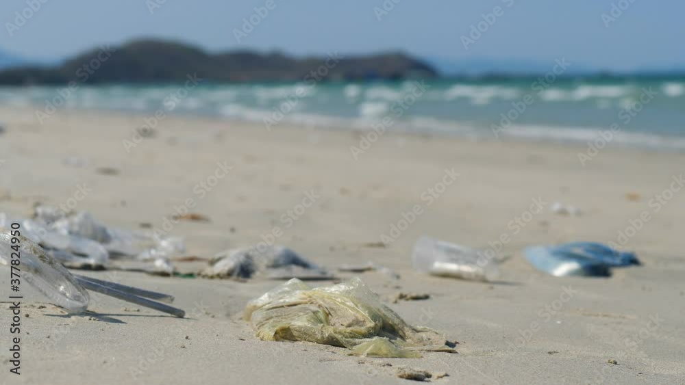 Close up of plastic bags, used straws and plastic cup on the sand at the beach. Close up of plastic bags, used straws and plastic cup on the sand at the beach.