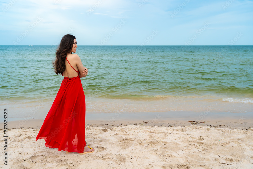 happy woman in red dress standing with arms crossed on sea beach happy woman in red dress standing with arms crossed on sea beach