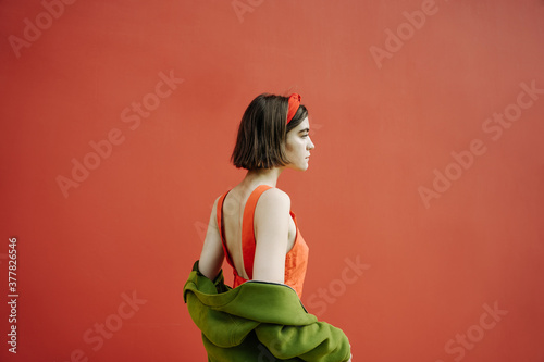 beautiful profile of young skinny girl in red dress and green jacket on background. Emotional bright saturated cheerful color combination. Conceptual artistic composition. Dramatic dreams and hopes photo