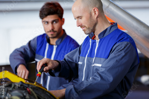mechanic and apprentice working on car together