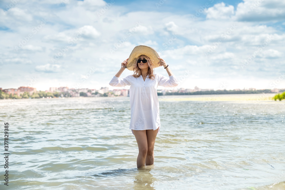 woman in white blouse and straw hat resting on a hot summer day walking on lake woman in white blouse and straw hat resting on a hot summer day walking on lake