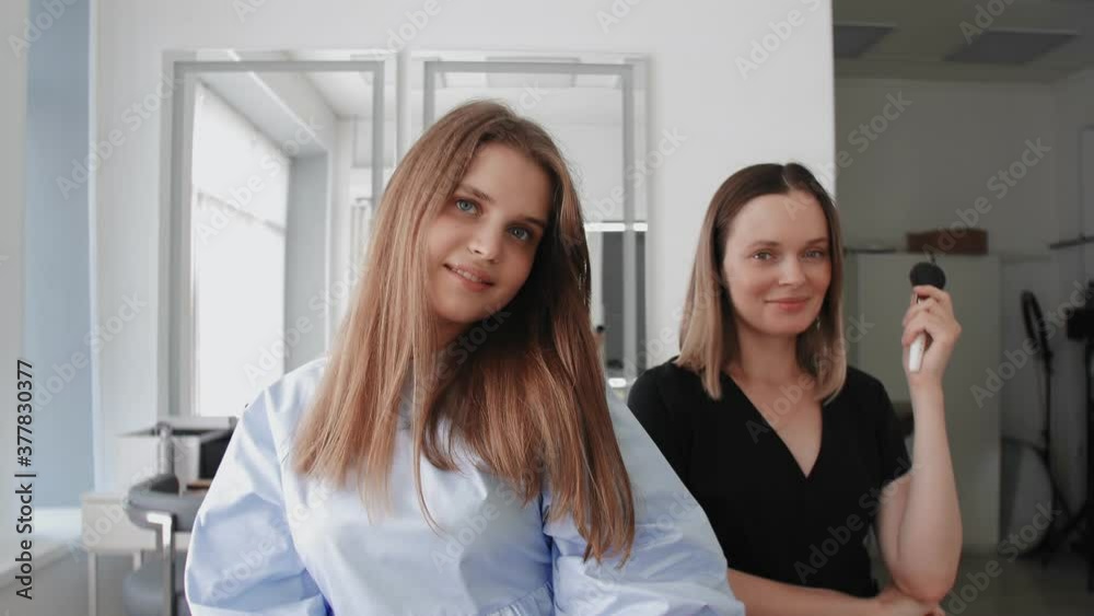 Confident caucasian adult makeup artist with young pupil in beauty studio, they posing at camera, after master class, share experience. Confident caucasian adult makeup artist with young pupil in beauty studio, they posing at camera, after master class, share experience.