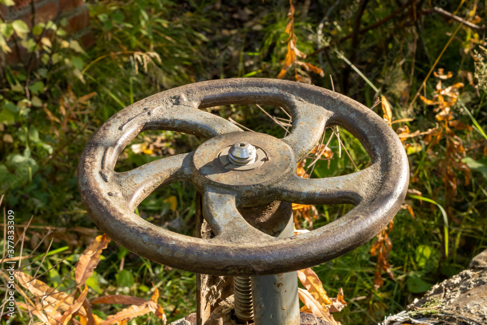 Old rusty valve close up on greenery background. Old rusty valve close up on greenery background.