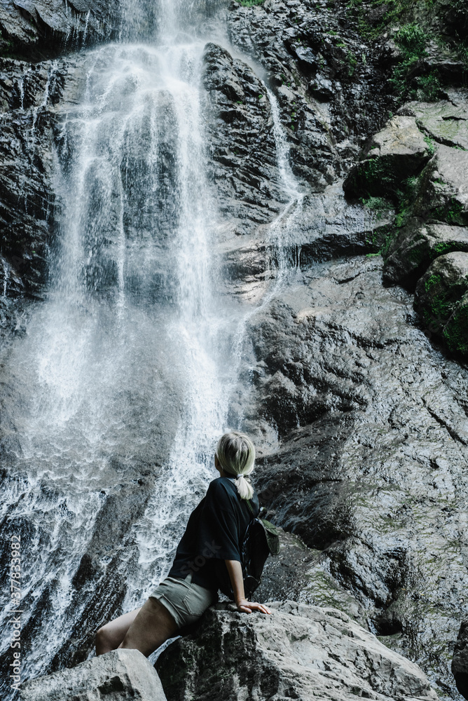 young woman on the background of a mountain waterfall with a ponytail 