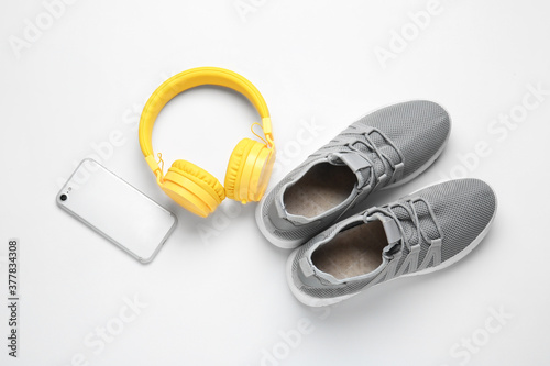 Sportive shoes, mobile phone and headphones on white background
