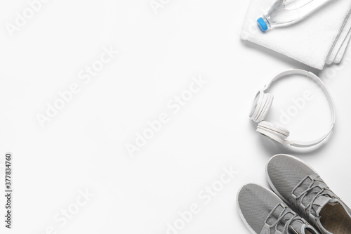 Sportive shoes, bottle of water, headphones and towel on white background