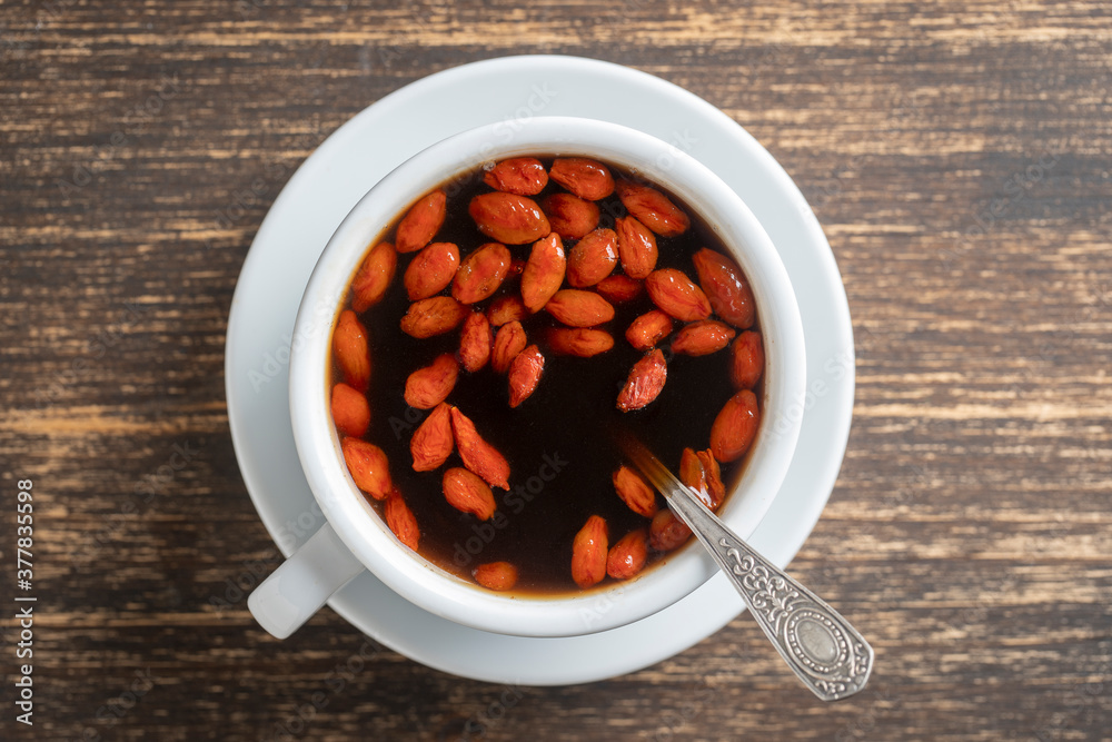 White cup of fresh morning goji coffee on wooden table, top view, close up White cup of fresh morning goji coffee on wooden table, top view, close up