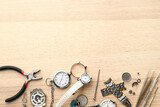 Watches and tools for repair on wooden background