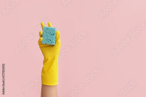 Hand in rubber glove and with sponge on color background