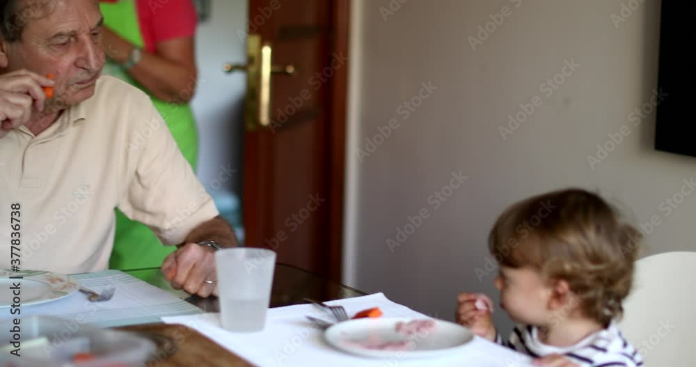 Family at meal table, grandfather with baby grandchild eating lunch Family at meal table, grandfather with baby grandchild eating lunch