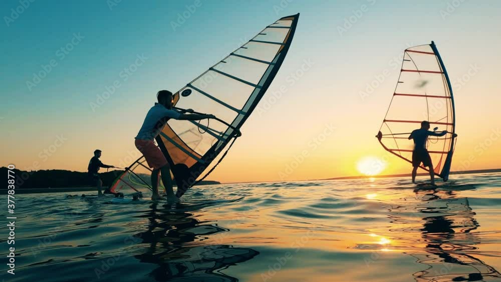 Group of men are trying to manage sails of windsurf boards