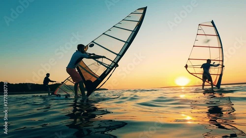 Group of men are trying to manage sails of windsurf boards photo