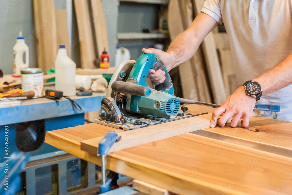 A man works with a circular saw in a carpentry workshop. Center A man works with a circular saw in a carpentry workshop. Center