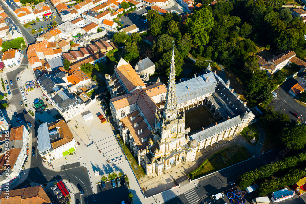 View from drone of houses and ancient Roman Catholic Cathedral of Lucon town at summer day, France