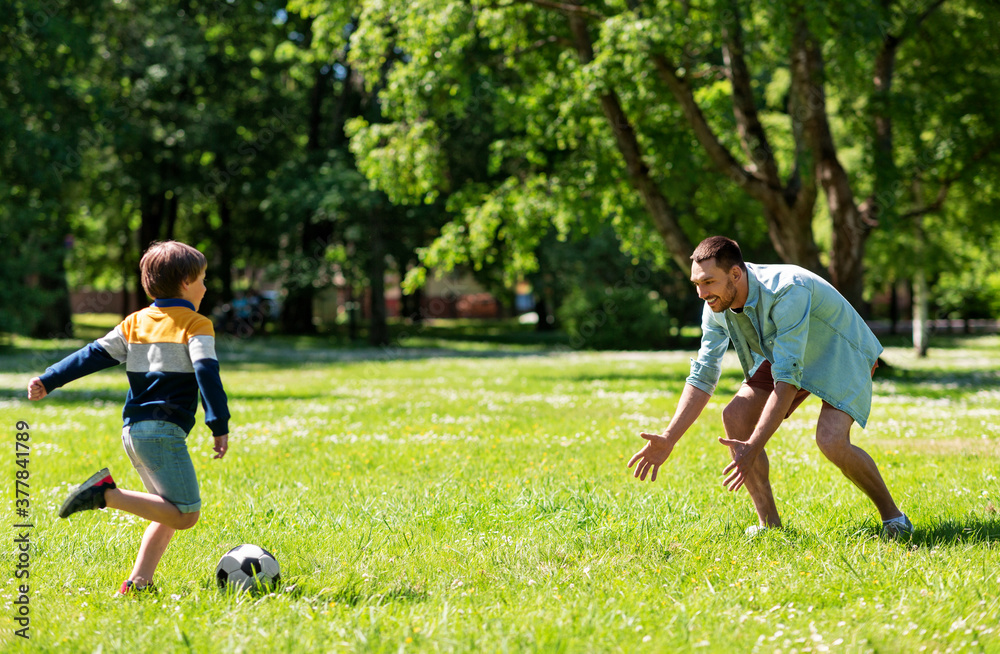 family, fatherhood and people concept - happy father and little son with ball playing soccer at summer park family, fatherhood and people concept - happy father and little son with ball playing soccer at summer park