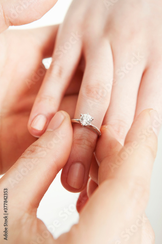 man placing a ring on woman's hand