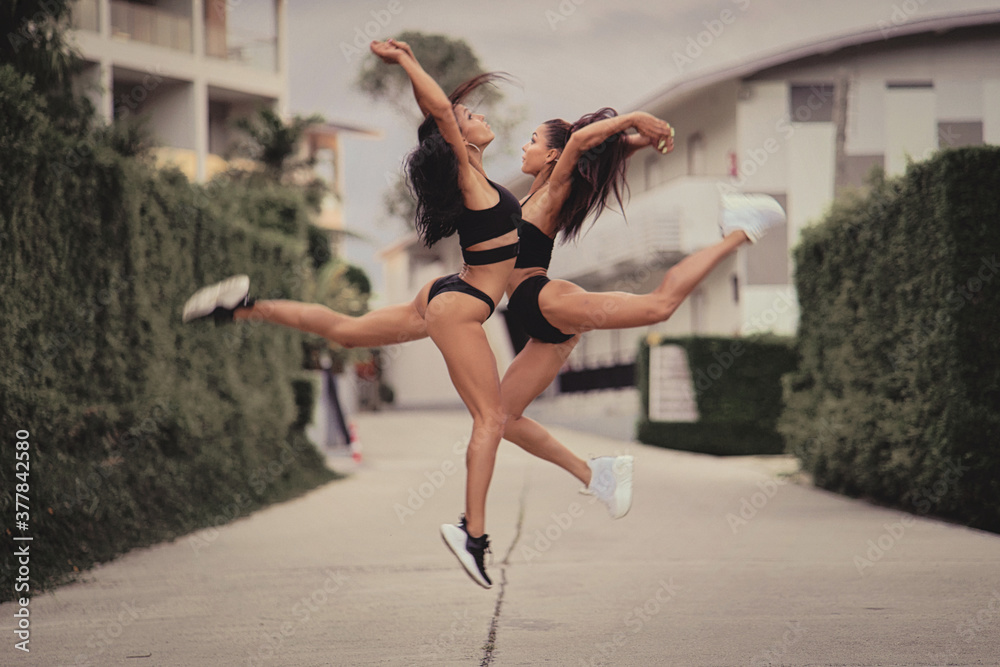 Two beautiful twin sisters Outdoor portrait. beautiful athletic slim bodied twin girls brunettes with long hair