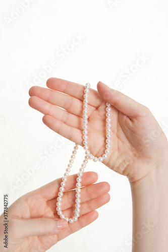 woman's hands holding necklace on white background