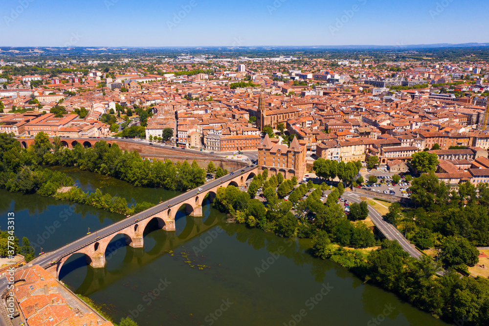 Picturesque view from drone of summer cityscape of Montauban with arched Old Bridge over river Tarn in summer day, Occitanie, France