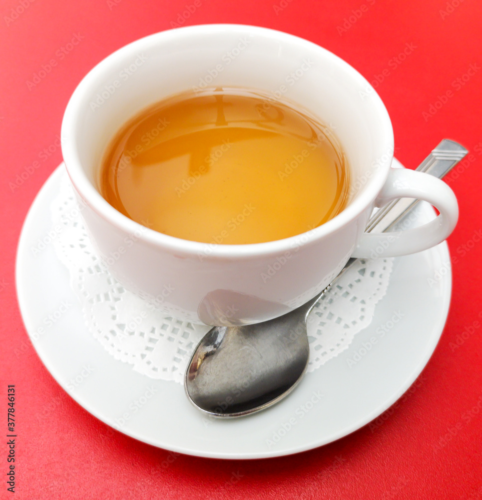 A tea cup with a spoon on a red A tea cup with a spoon on a red