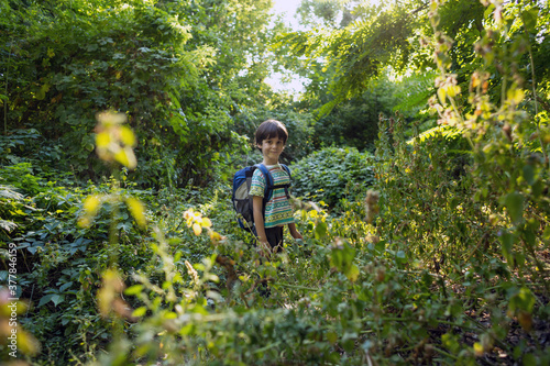 A boy with a backpack walks in the meadow