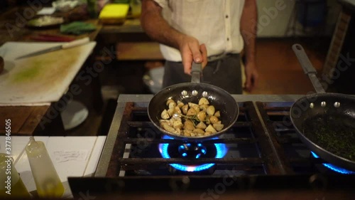 chef hand sautéing potatoes with a frying pan on the stove photo