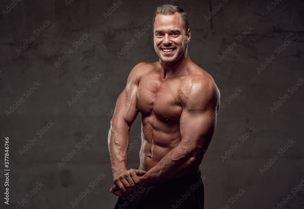 Confident and strong guy with musculate body posing in special grung background. Healthy lifestyle.