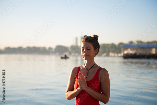 Woman meditating and practising yoga during sunrise in paddle board