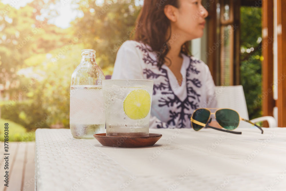 Φωτογραφία Healthy nutrition of sparkling water with slice of lime and woman in background