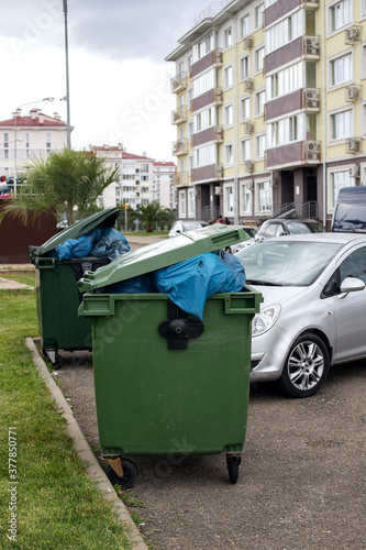 dark green trash can on a city street © Арина Макаренко
