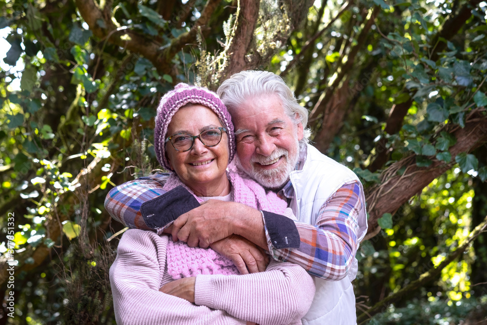 Portrait of attractive couple of senior man and woman enjoying mountain excursion in the woods at fall season, embracing and smiling looking at camera - active retired elderly and fun concept Portrait of attractive couple of senior man and woman enjoying mountain excursion in the woods at fall season, embracing and smiling looking at camera - active retired elderly and fun concept