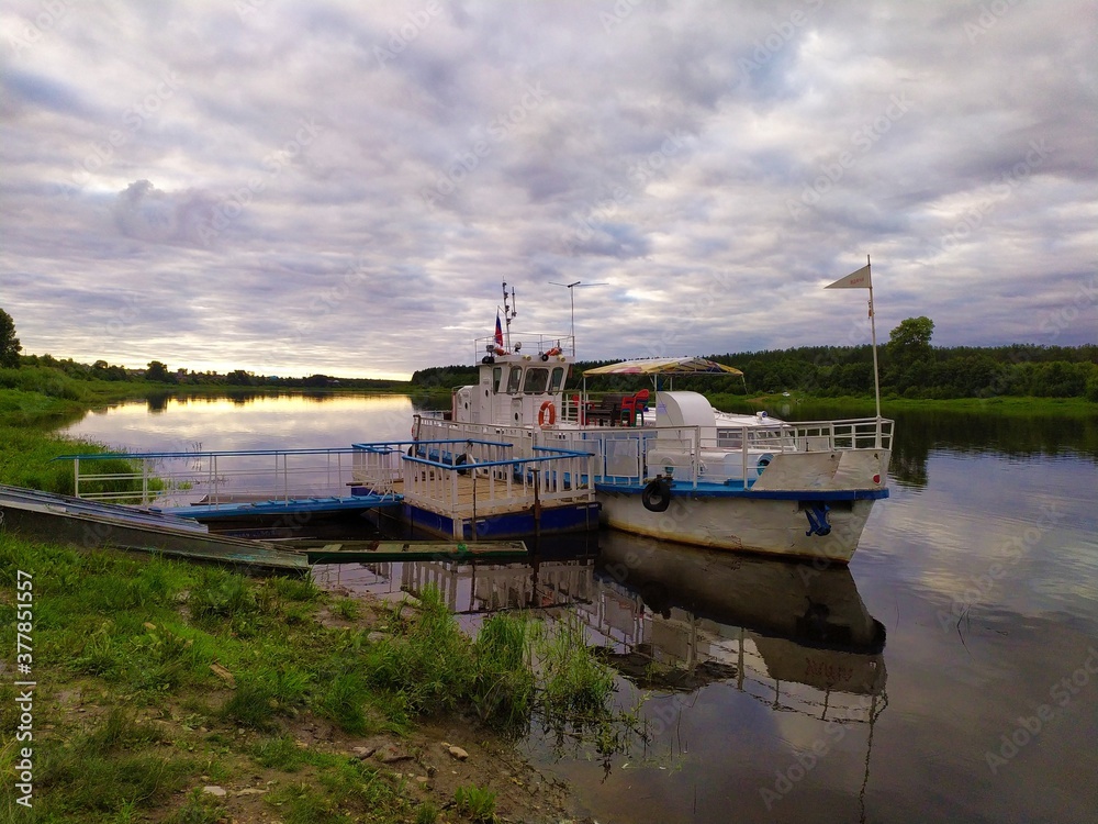 Fototapeta premium White old pleasure boat on the river bank at sunset