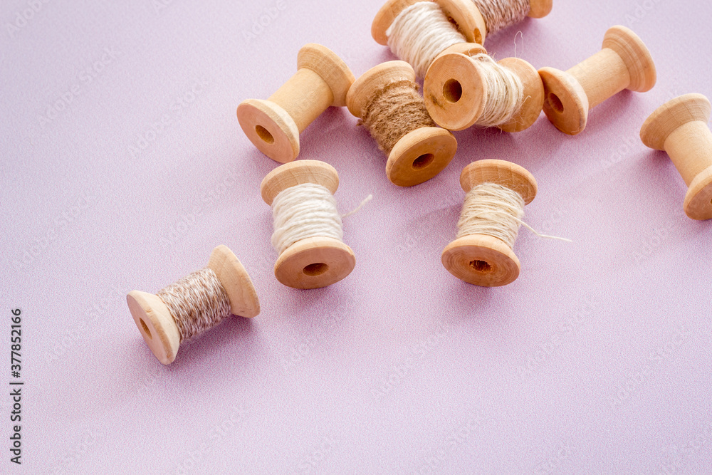 Wooden spools of thread for sewing on lilac background Wooden spools of thread for sewing on lilac background