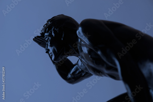 Giovane uomo con lo sguardo all’orizzonte  scultura Art Decò in gesso, patinata in nero lucido, particolare su fondo blu con spazio per testo © Enzo Pancaldi