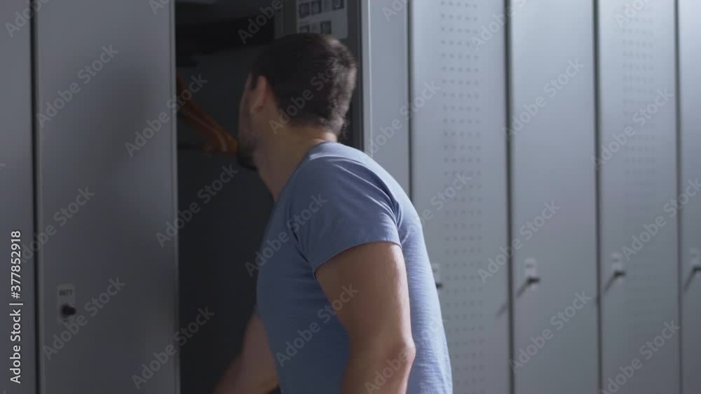 Caucasian young sportsman opening locker with keyless bracelet and drinking refreshing water. Portrait of athletic confident man after training in gym. Sport and masculinity concept. Caucasian young sportsman opening locker with keyless bracelet and drinking refreshing water. Portrait of athletic confident man after training in gym. Sport and masculinity concept.