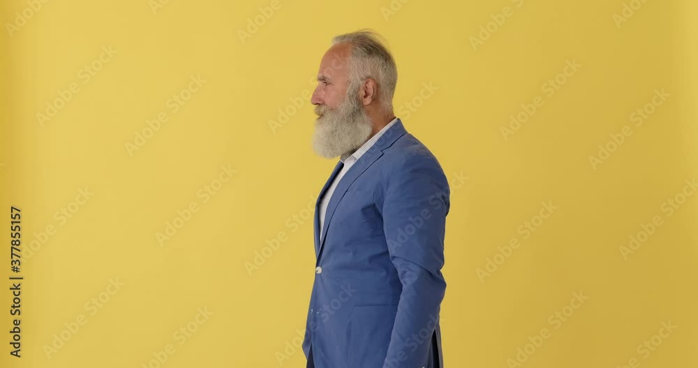 Profile of angry senior businessman showing middle finger over yellow background Profile of angry senior businessman showing middle finger over yellow background