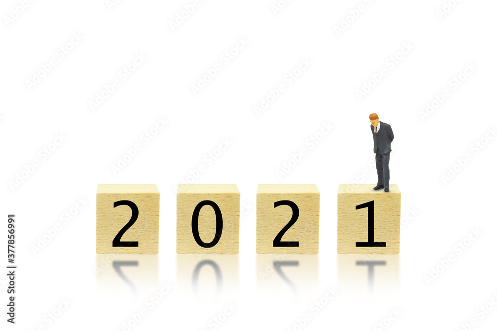 Business and 2021 New Year Concept : Miniature as businessman bend down to look at 2021 wording text on wooden blocks. Business and 2021 New Year Concept : Miniature as businessman bend down to look at 2021 wording text on wooden blocks.