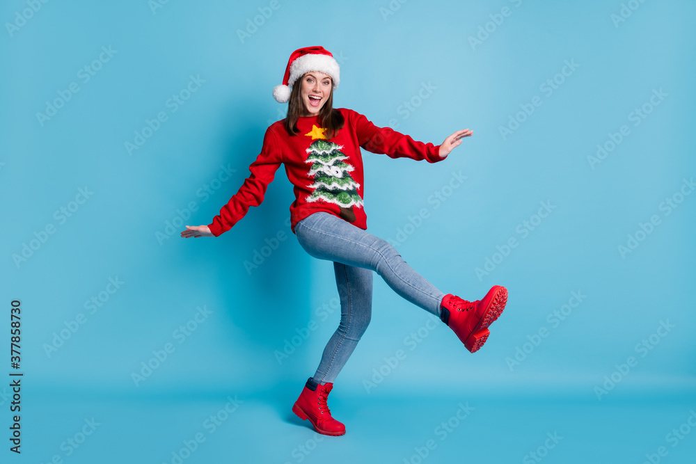 Full body size photo of charming pretty lady raise hands leg dance open mouth wear santa x-mas headwear red ornamented pullover boots jeans isolated blue color background