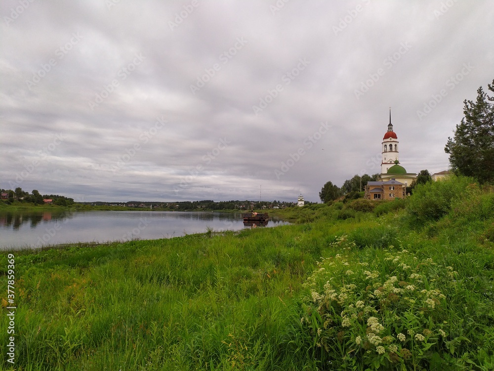 Rural landscape with calm river and white church on the shore,Russia