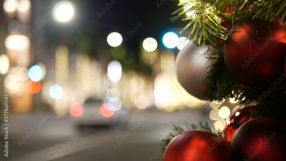 Closeup of Festively Decorated Outdoor Christmas tree with bright red balls on blurred sparkling fairy background. Defocused garland lights, Bokeh effect. Defocused night city street with cars on road Closeup of Festively Decorated Outdoor Christmas tree with bright red balls on blurred sparkling fairy background. Defocused garland lights, Bokeh effect. Defocused night city street with cars on road