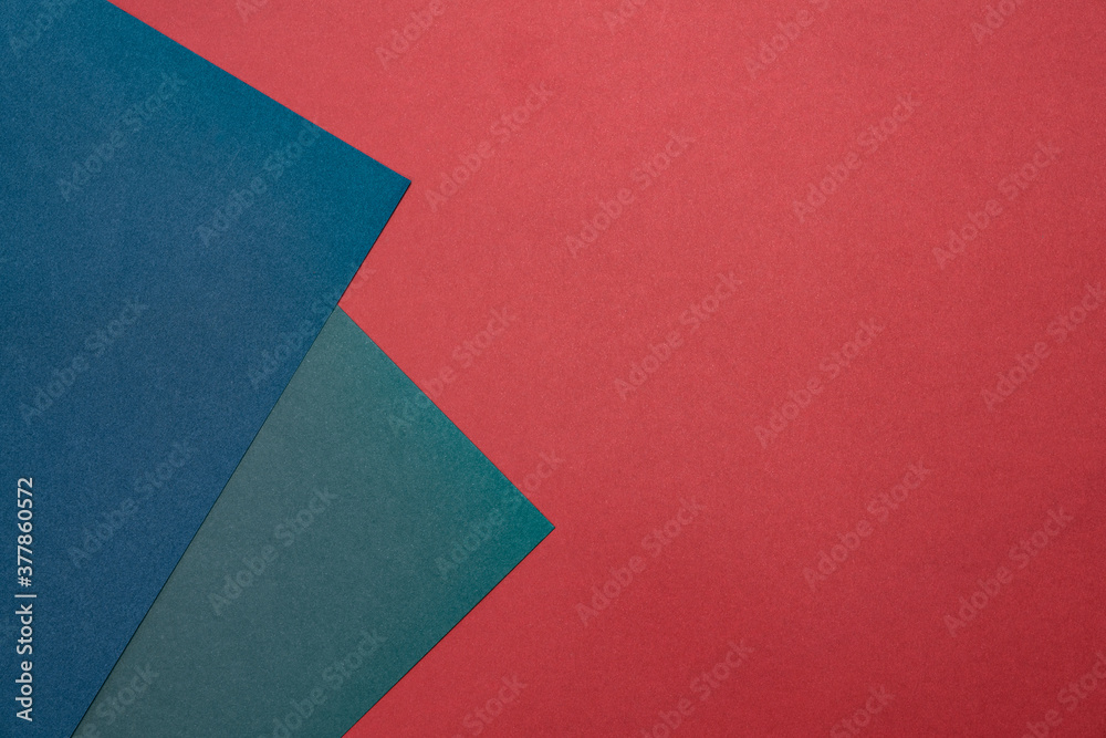 Two sheets of colored paper on a red background. Blue, green, blue. Minimalistic composition. Background for text or design. Empty right side. Top view Two sheets of colored paper on a red background. Blue, green, blue. Minimalistic composition. Background for text or design. Empty right side. Top view